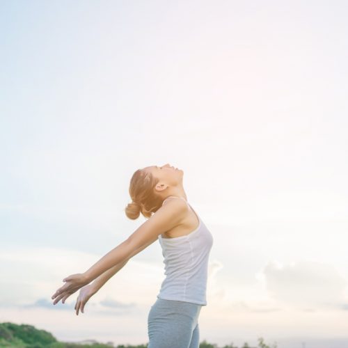 concentrated-woman-stretching-her-arms-with-sky-background